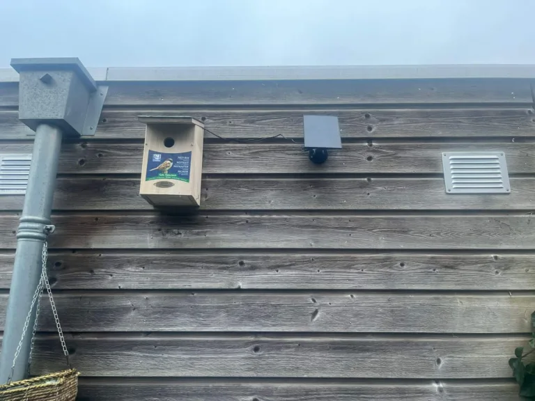 Vogelhuisje met camera en zonnepaneel van onder gefotografeerd